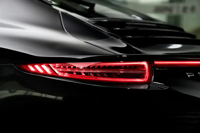 Glossy black sports car rear with red tail lights