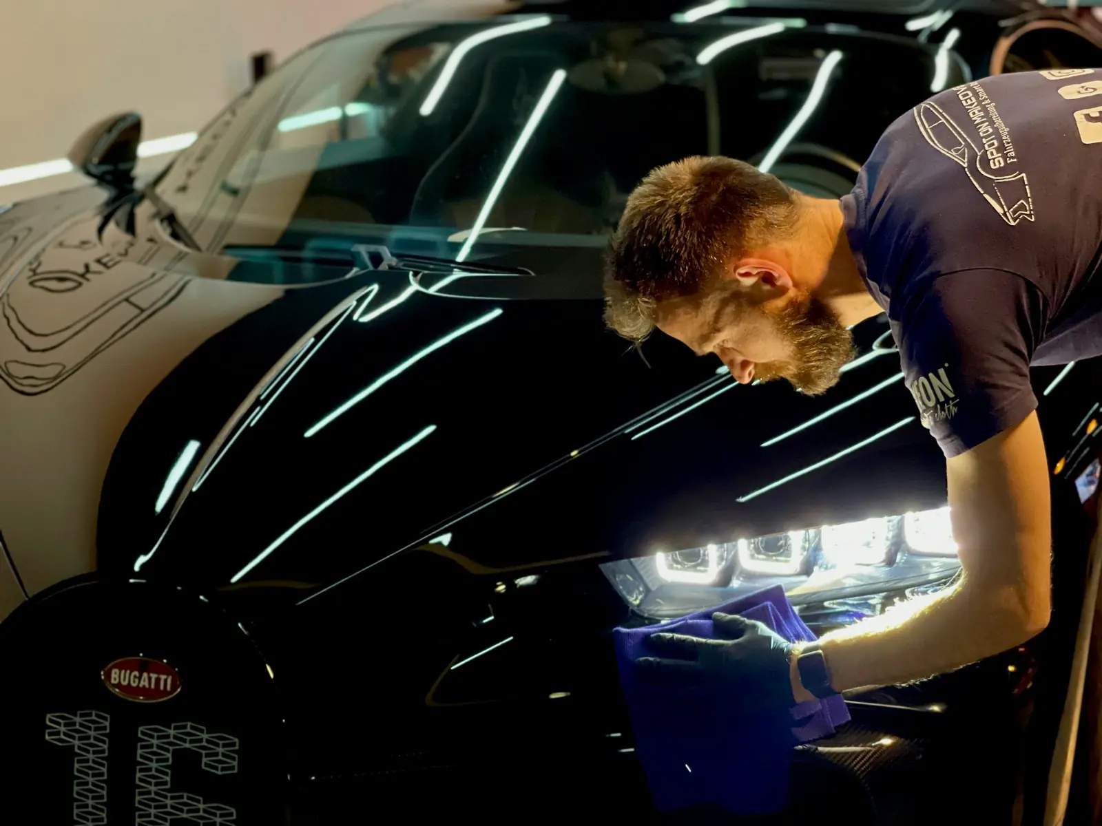 Detailer polishing a glossy black car to a mirror finish